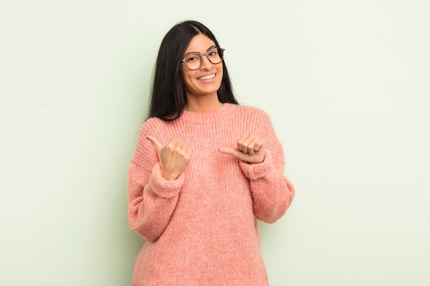 Sorrindo alegremente e casualmente apontando para copiar o espaço ao lado sentindo-se feliz e satisfeito