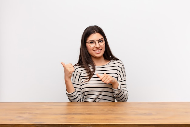 sorrindo alegremente e casualmente apontando para copiar o espaço ao lado, sentindo-se feliz e satisfeito