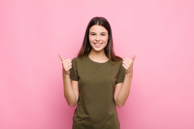 sorrindo alegremente e feliz, sentindo-se despreocupado e positivo com os dois polegares para cima