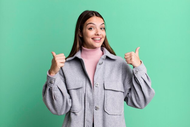 Sorrindo alegremente e parecendo feliz sentindo-se despreocupado e positivo com os dois polegares para cima