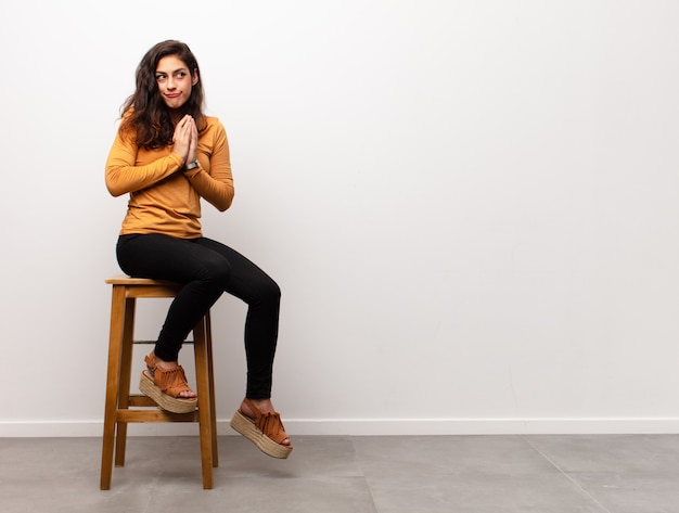 sorrindo alegremente jovem mulher sentada em uma cadeira ao lado de copyspace