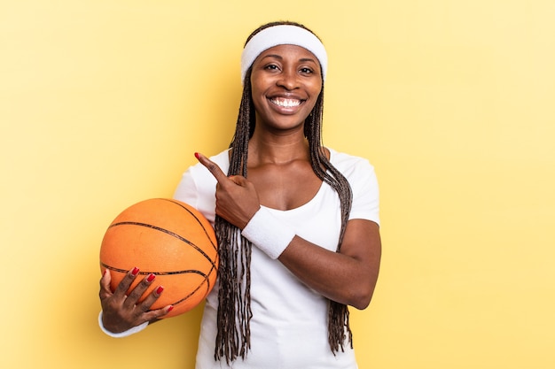 Sorrindo alegremente, sentindo-se feliz e apontando para o lado e para cima, mostrando o objeto no espaço da cópia. conceito de cesta