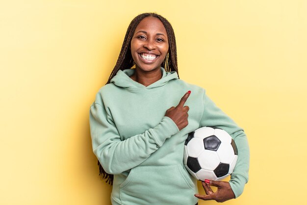 Sorrindo alegremente, sentindo-se feliz e apontando para o lado e para cima, mostrando o objeto no espaço da cópia. conceito de futebol