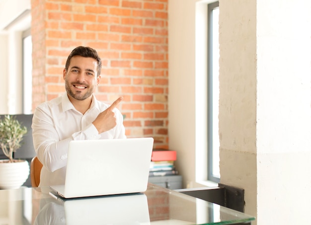 Sorrindo alegremente, sentindo-se feliz e apontando para o lado e para cima, mostrando o objeto no espaço da cópia