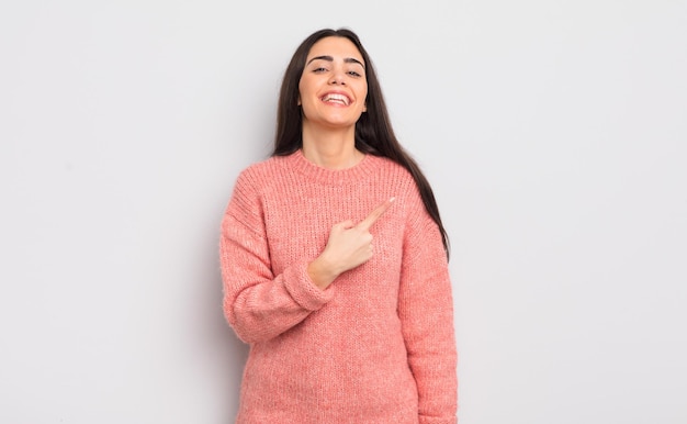 sorrindo alegremente sentindo-se feliz e apontando para o lado e para cima mostrando o objeto no espaço da cópia