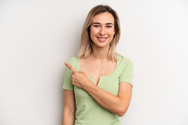 Sorrindo alegremente sentindo-se feliz e apontando para o lado e para cima mostrando o objeto no espaço da cópia