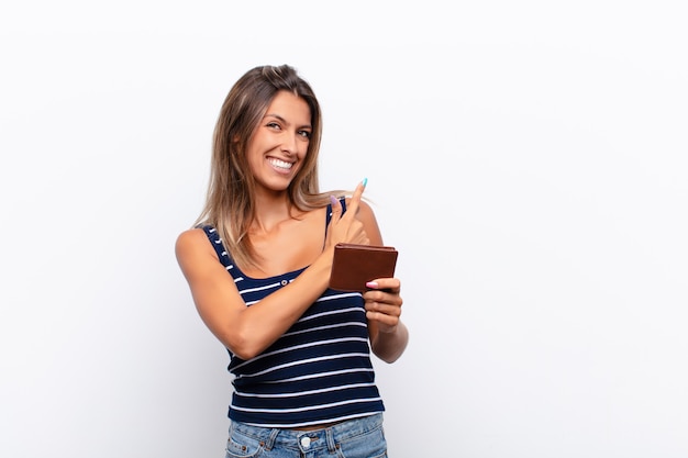 sorrindo alegremente, sentindo-se feliz e apontando para o lado e para cima, mostrando o objeto no espaço da cópia