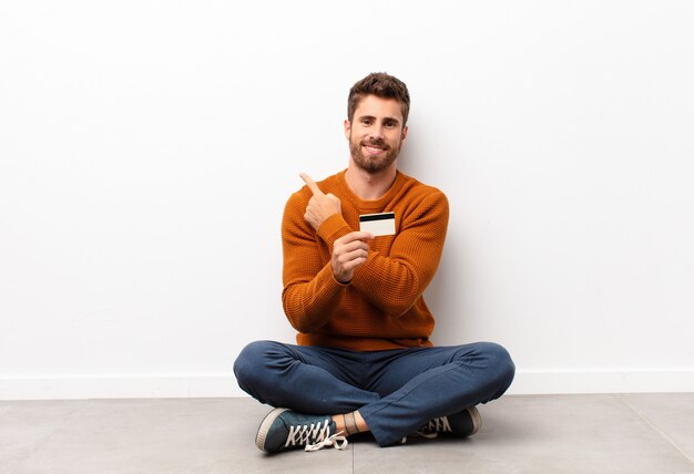 Sorrindo alegremente, sentindo-se feliz e apontando para o lado e para cima, mostrando o objeto no espaço da cópia