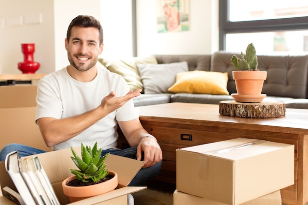 sorrindo alegremente, sentindo-se feliz e mostrando um conceito no espaço da cópia com a palma da mão