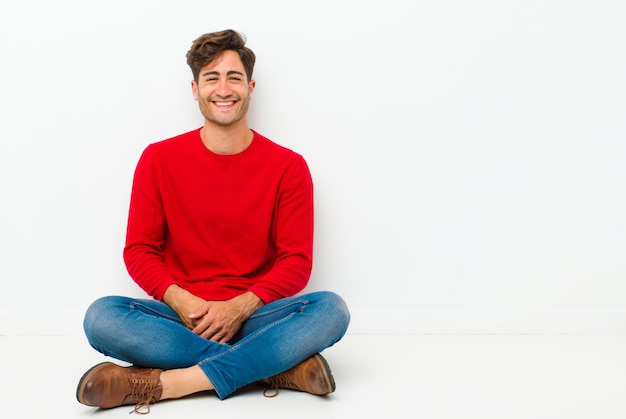 sorrindo alegremente, sentindo-se feliz, satisfeito e relaxado, com os braços cruzados e olhando para o lado