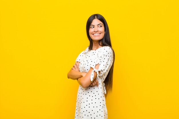 sorrindo alegremente, sentindo-se feliz, satisfeito e relaxado, com os braços cruzados e olhando para o lado