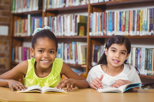 Sorrindo alunos lendo livros na biblioteca