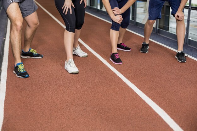 Sorrindo amigos atléticos vai começar a correr na pista