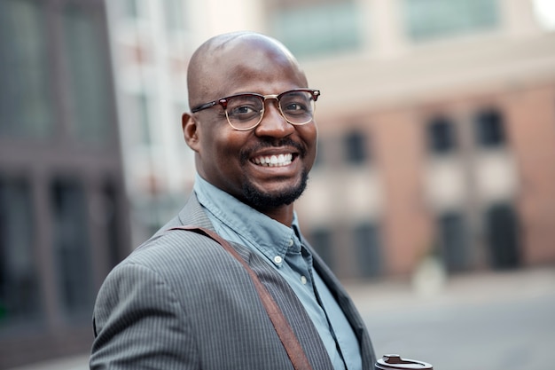 Sorrindo amplamente. Empresário barbudo, de pele escura, sorrindo amplamente enquanto se sente motivado