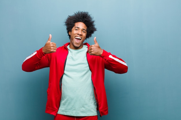 sorrindo amplamente olhando feliz, positivo, confiante e bem-sucedido, com os dois polegares para cima