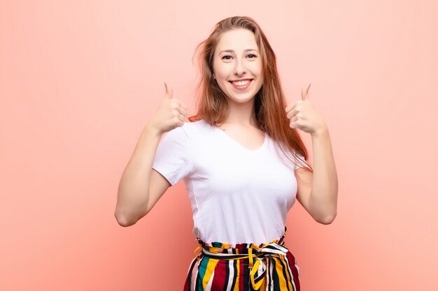 sorrindo amplamente olhando feliz, positivo, confiante e bem-sucedido, com os dois polegares para cima