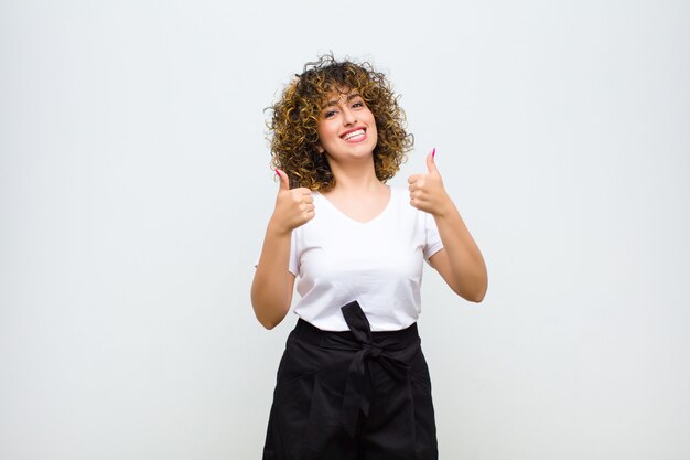 Sorrindo amplamente olhando feliz, positivo, confiante e bem-sucedido, com os dois polegares para cima