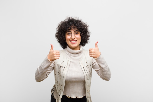 sorrindo amplamente olhando feliz, positivo, confiante e bem-sucedido, com os dois polegares para cima