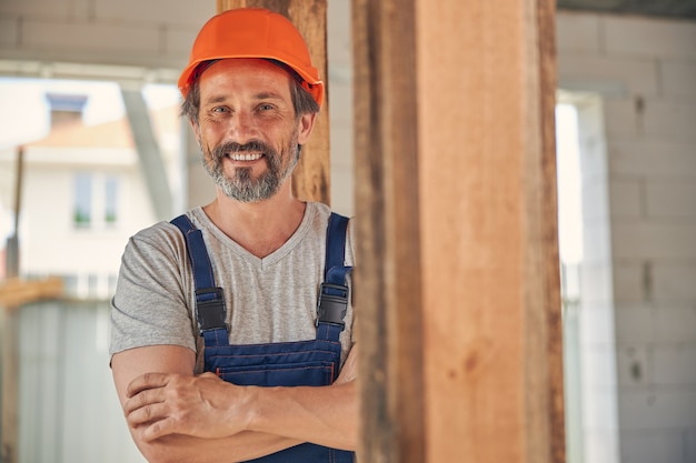 sorrindo apto trabalhador da construção civil com os braços cruzados sorrindo para a câmera