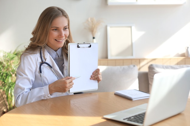 Sorrindo atraente médica falando para a câmera com o paciente.