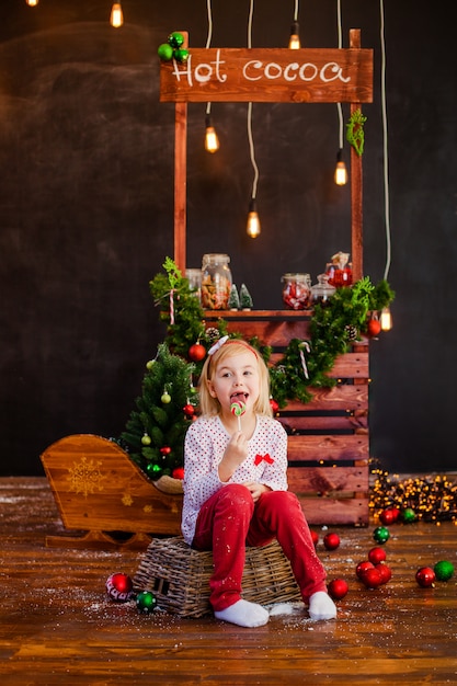 Sorrindo bela loira sentada no chão de madeira com bolas de Natal