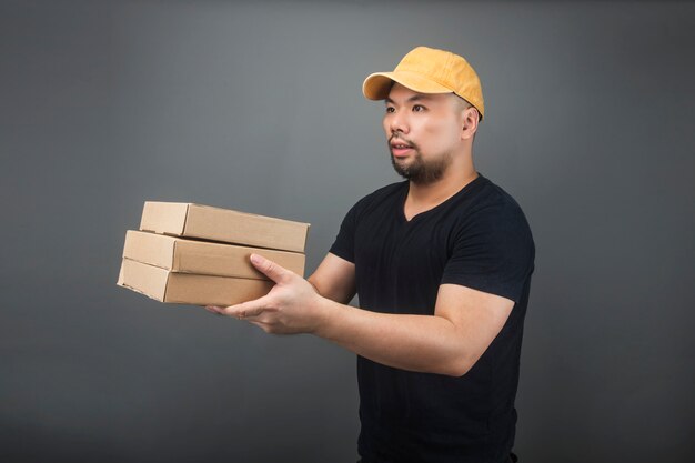 Sorrindo bonito asiática entrega homem vestindo boné, dando e carregando parcela, caixa de papelão, mudança de dia de casa e entrega expressa conceito