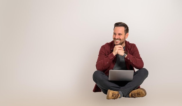 Foto sorrindo bonito empresário masculino com as mãos entrelaçadas, olhando para longe enquanto está sentado