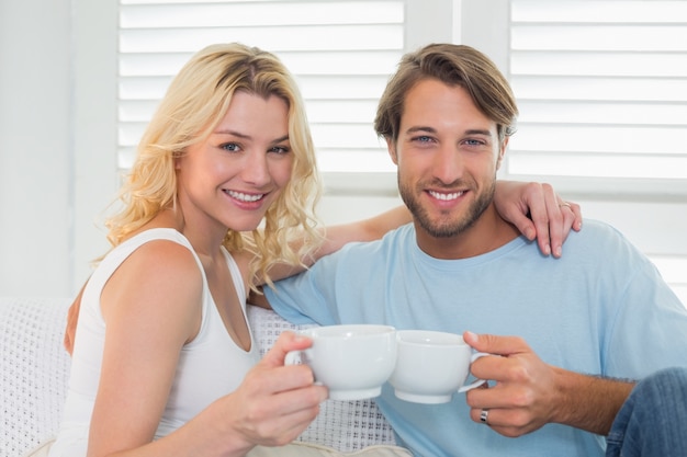 Sorrindo casal casado sentado no sofá tomando café