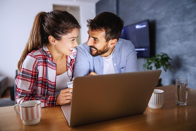 Sorrindo casal feliz sentado em casa e usando tablet para compras online