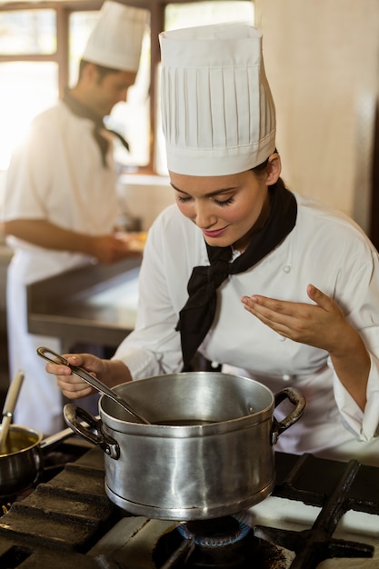 Sorrindo chefe de cozinha mexendo na panela