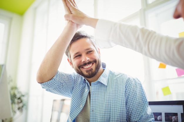 Sorrindo colegas de trabalho dando mais cinco no escritório criativo