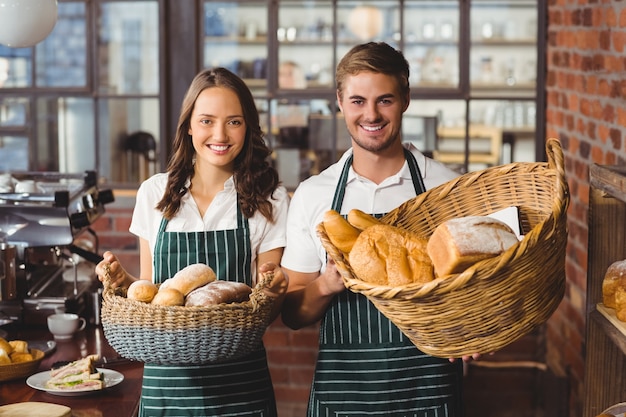 Sorrindo colegas de trabalho segurando cesta de pães