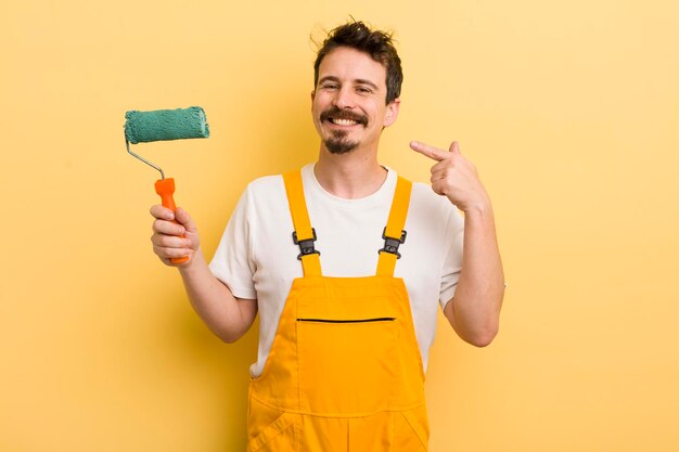 Sorrindo com confiança, apontando para o próprio conceito de casa de pintura de sorriso amplo