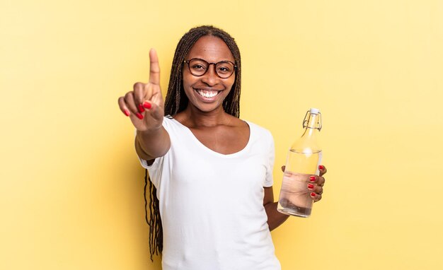 Sorrindo com orgulho e confiança fazendo a pose número um de forma triunfante, sentindo-se um líder. conceito de garrafa de água