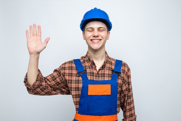 Sorrindo com os olhos fechados, mostrando cinco jovens construtores do sexo masculino vestindo uniforme