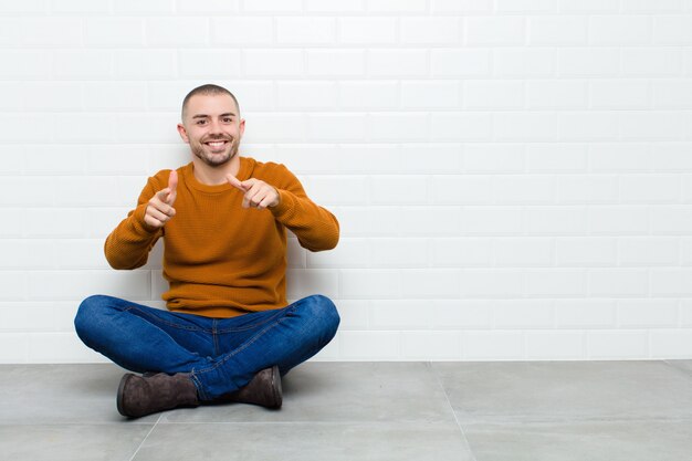 sorrindo com uma atitude positiva, bem-sucedida e feliz apontando, fazendo sinal de arma com as mãos