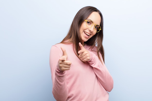 sorrindo com uma atitude positiva, bem-sucedida e feliz apontando, fazendo sinal de arma com as mãos