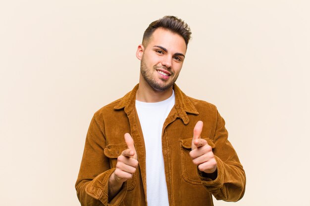 sorrindo com uma atitude positiva, bem-sucedida e feliz, apontando para a frente, fazendo sinal de arma com as mãos