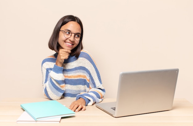 sorrindo com uma expressão feliz e confiante com a mão no queixo, pensando e olhando para o lado