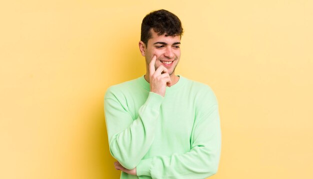 Sorrindo com uma expressão feliz e confiante com a mão no queixo pensando e olhando para o lado