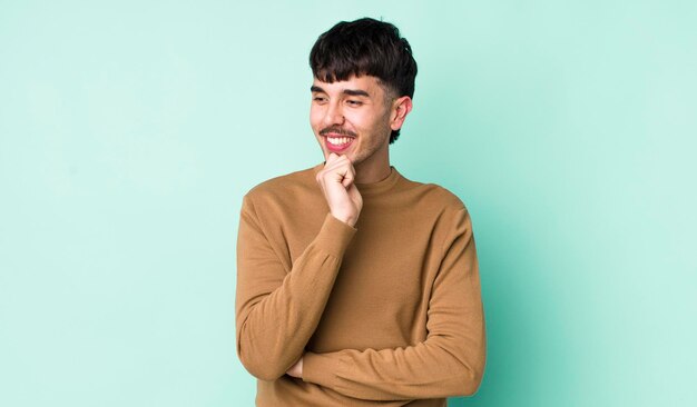 Sorrindo com uma expressão feliz e confiante com a mão no queixo pensando e olhando para o lado