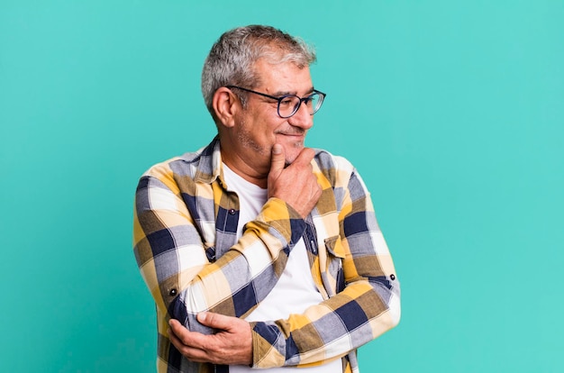 Foto sorrindo com uma expressão feliz e confiante com a mão no queixo pensando e olhando para o lado