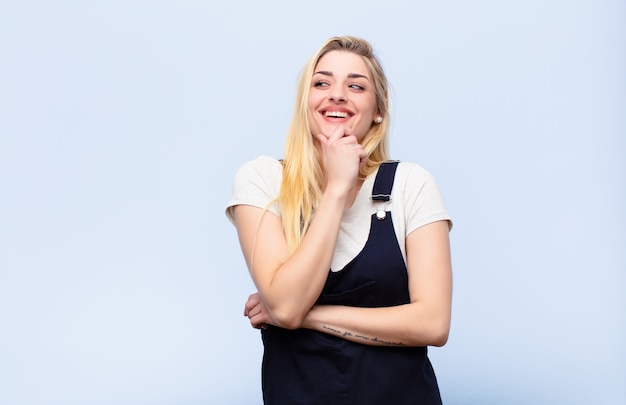 sorrindo com uma expressão feliz e confiante com a mão no queixo, pensando e olhando para o lado