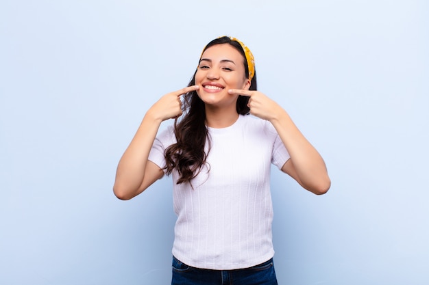 sorrindo confiante apontando para o próprio sorriso largo, atitude positiva, relaxada e satisfeita