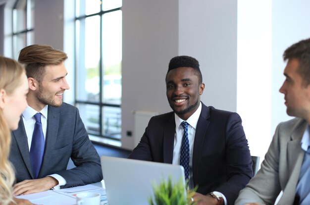 Sorrindo confiante empresário africano em uma reunião com colegas sentados em uma mesa de conferência no escritório.