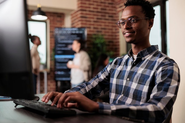 Sorrindo confiante engenheiro de software afro-americano desenvolvendo algoritmo de aprendizado de máquina para sustentar a estabilidade da segurança do sistema. Desenvolvedor cibernético criando rede usando criptografia binária.