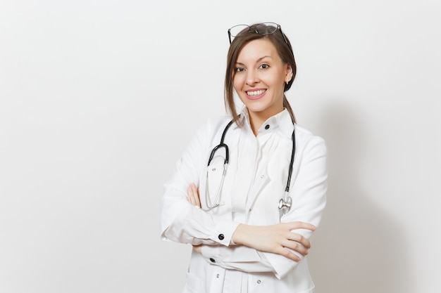 Sorrindo confiante linda jovem médica com estetoscópio, óculos isolados no fundo branco. Médica em vestido de médico mantém as mãos postas. Pessoal de saúde, saúde, conceito de medicina.