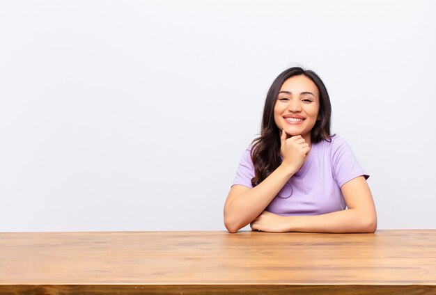 sorrindo, curtindo a vida, sentindo-se feliz, amigável, satisfeito e despreocupado com a mão no queixo