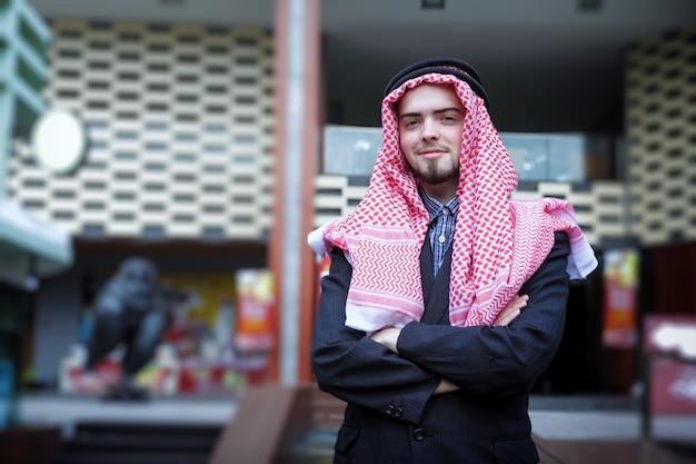 sorrindo de homem árabe de negócios usando a mão para pressionar o laptop. ao ar livre