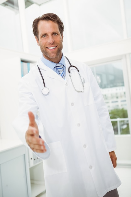 Foto sorrindo doutor oferecendo aperto de mão no consultório médico